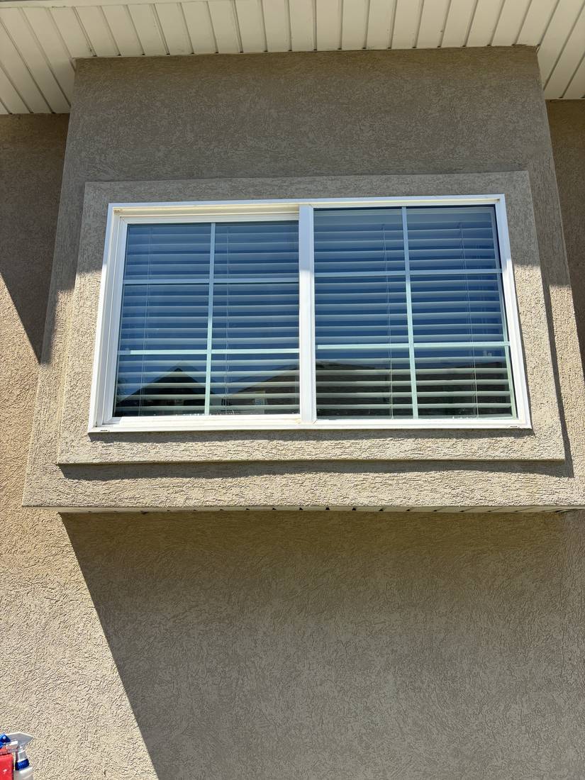 Tall home window cleaned spot-free with blinds visible through the glass